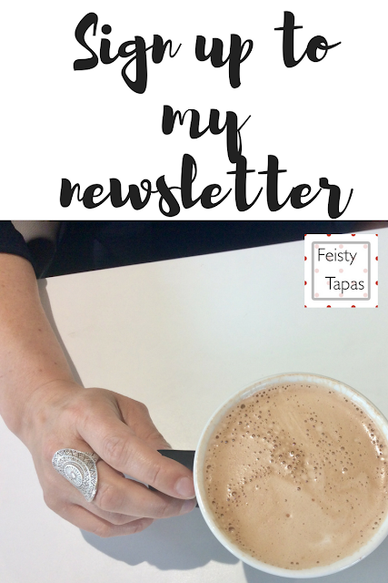 Graphic showing a hand with an oblong silver ring on the middle finger holding on to a coffee cup with a white rim, on a white table. the words Sign up to my Newsletter are above