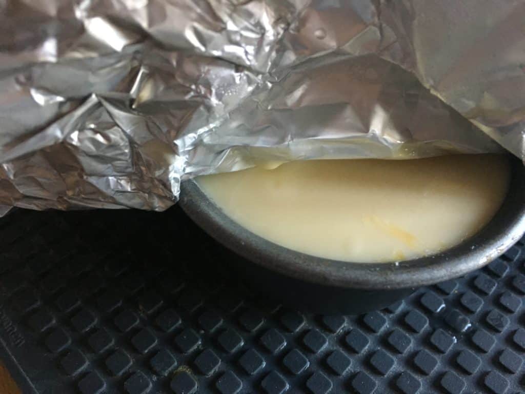 Photo of a sneak peek of pressure cooked flan de Huevo, the foil is lifted a little bit to show a bit of the flan