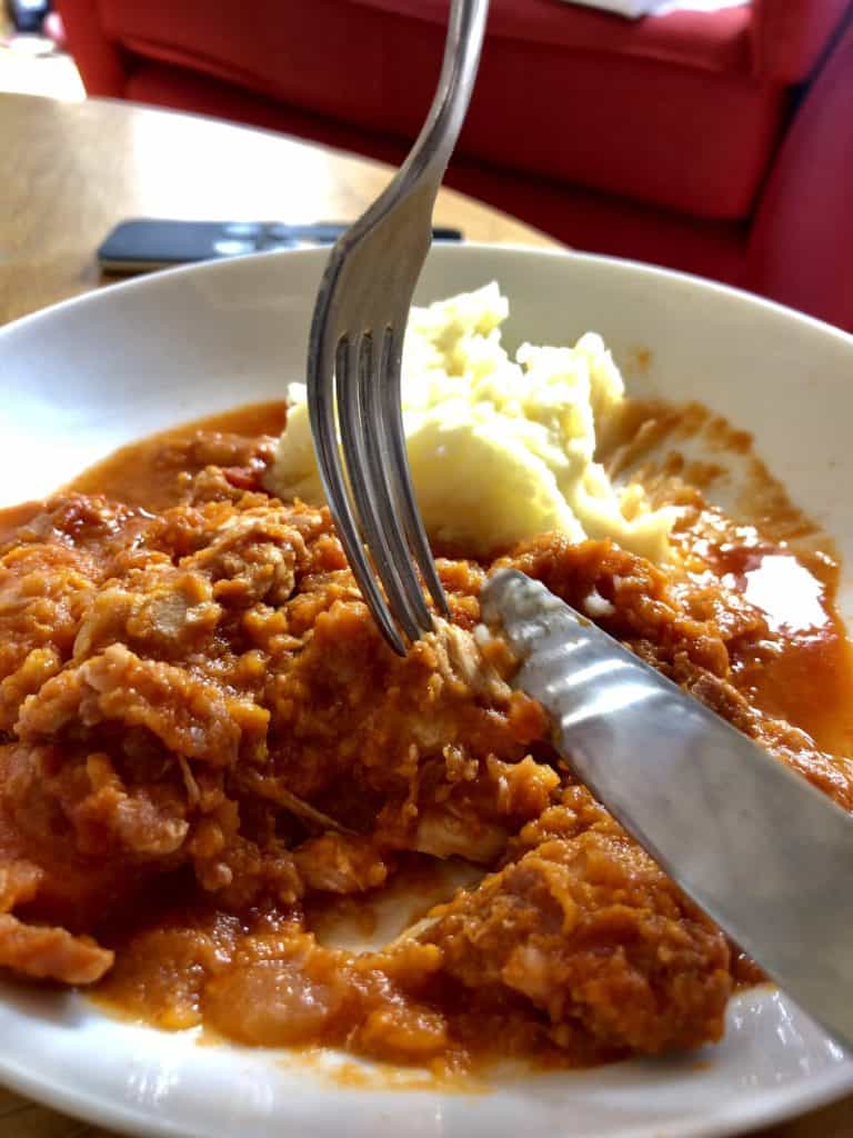 Photo of the pressure cooked turkey stew served on a white plate with a fork and knife tucking in