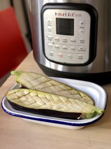 The sliced aubergine placed inside a white and blue enamel dish in front of an Instant Pot Duo Crisp