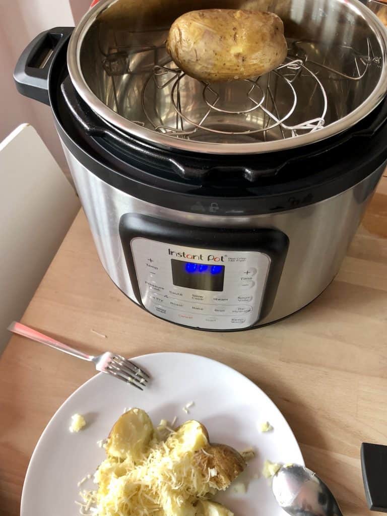 Instant Pot duo crisp baked potato view from above with potato still on trivet and other potato served with butter and cheese