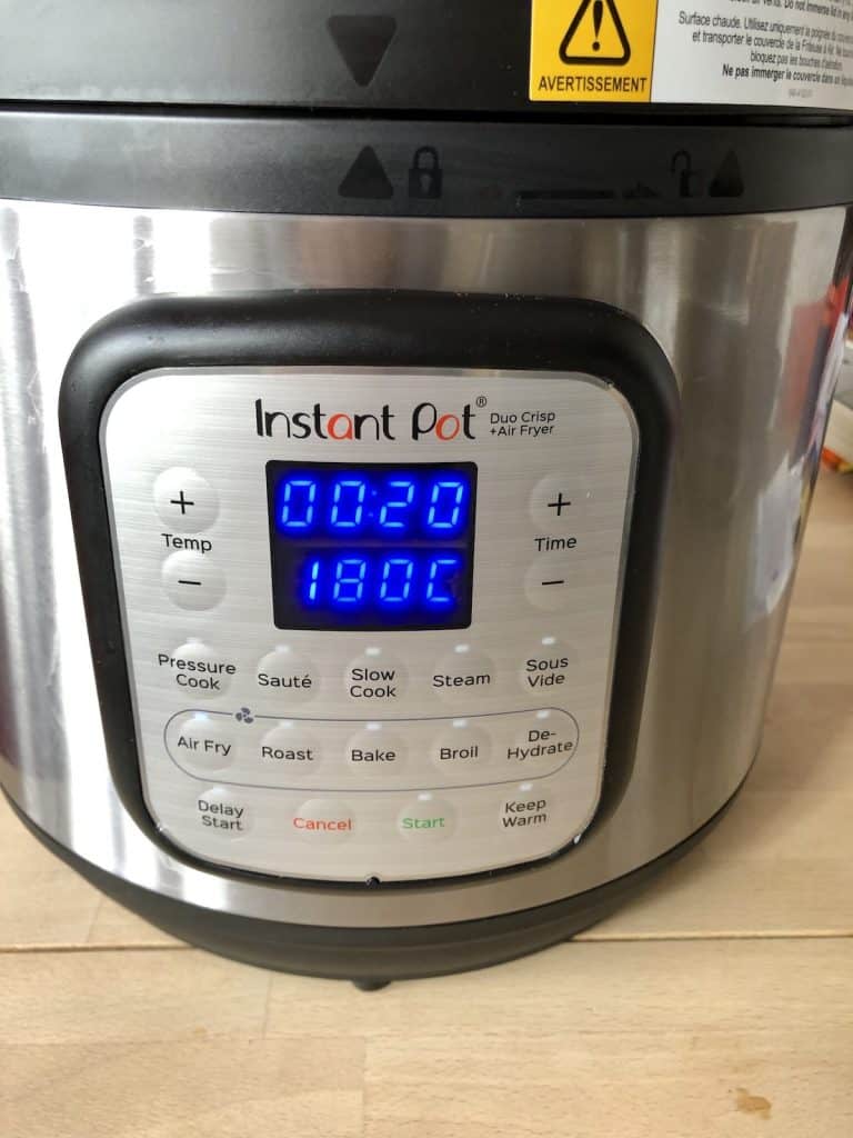 An Instant Pot Duo Crisp on a wooden table, the control panel says 20 minutes and 180ºC