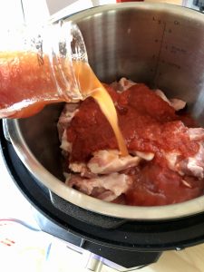 Photo of the water from rinsing passata jar being poured into Easy Instant Pot BBQ Pulled Pork recipe by Feisty Tapas