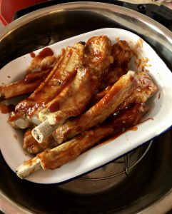 Photo of the basted pork ribs in a white enamel dish placed on the rack, ready to air fry with the air fryer lid of the Instant Pot Duo Crisp