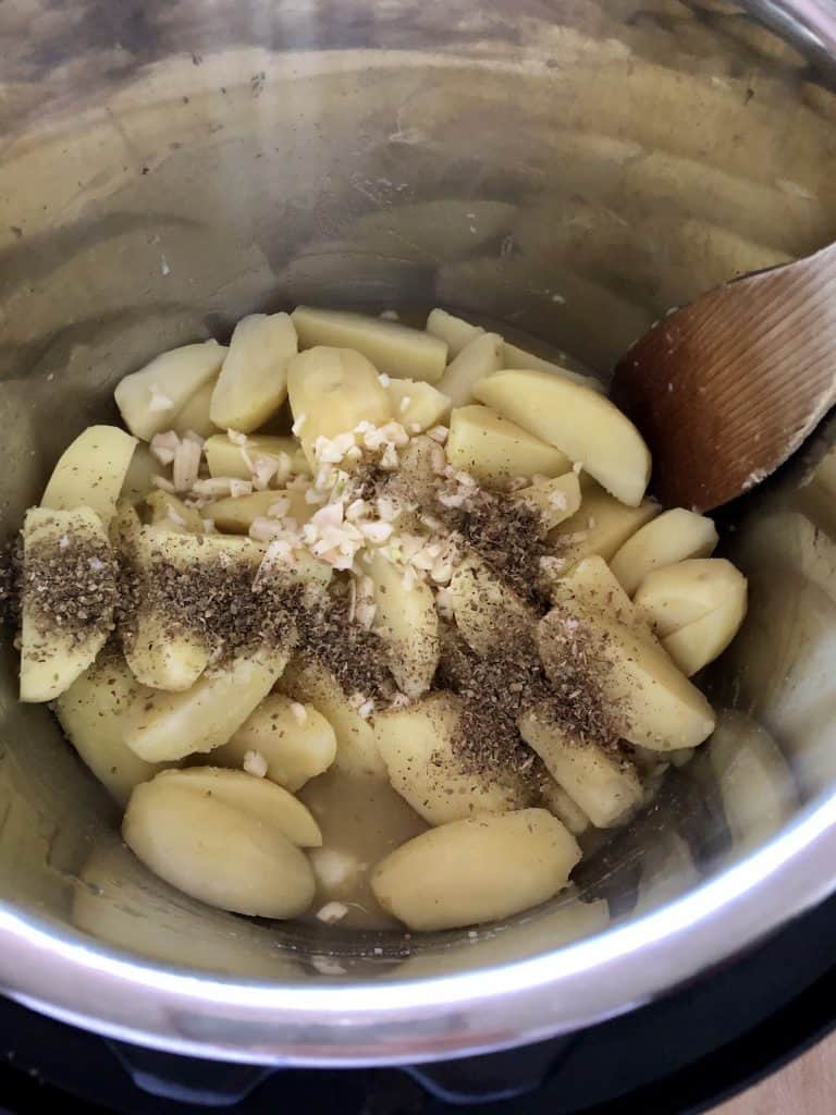 Photo of the raw potato wedges with garlic and herbs on top before roasting
