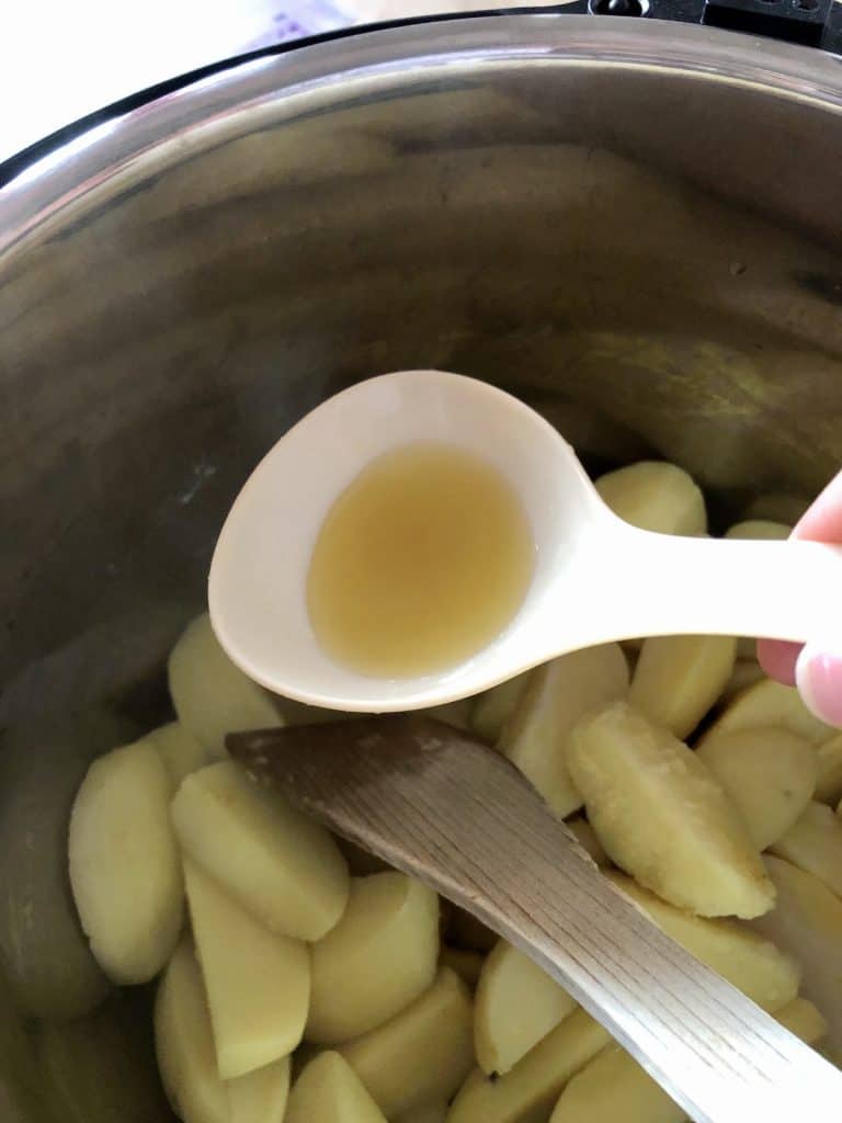 Photo of a ladle removing some of the stock from the pressure cooked potatoes