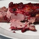 The Cranberry Sauce-Glazed Gammon joint on a white plate with a slice in front of it