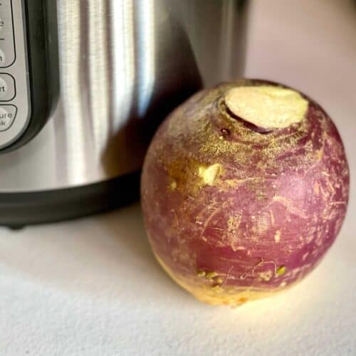Photo of a Whole Swede or Rutabaga (uncooked) on a white textured surface, in front of an Instant Pot Duo