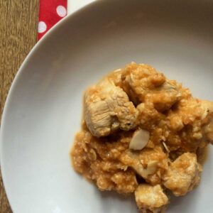 Pressure cooked turke stew (Escaldums) served on a white plate with a brown background and a red and white polka dot napkin, seen from above