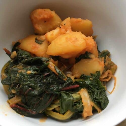 Pressure cooked chard with paprika and potatoes seen from above close up inside a white bowl or plate