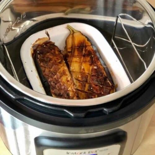 The Soy-Glazed Aubergine sliced in half and seen inside the Instant Pot Duo Crisp in a white enamel dish