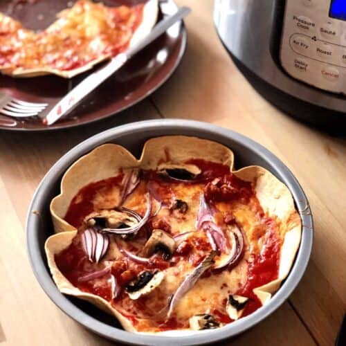 Photo of a tortilla pizza seen inside its cake pan with the Instant Pot Duo Crisp in the background