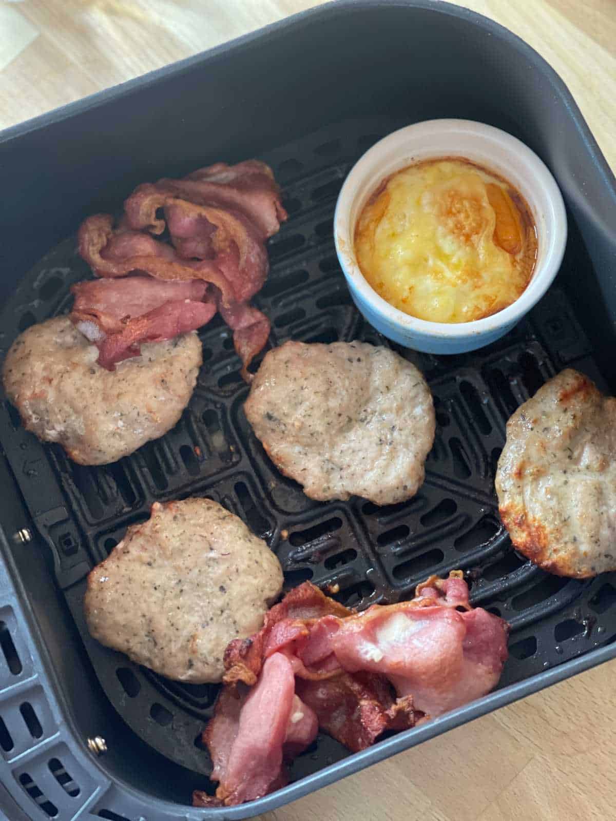 Photo of the bacon, sausage patties and eggs inside the air fryer drawer and ready to turn into McMuffins
