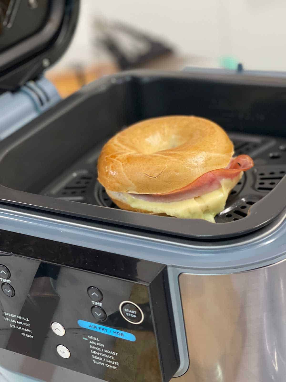 Photo of a delicious air fried bagel with melted cheese seen on the top shelf of the Ninja Speedi