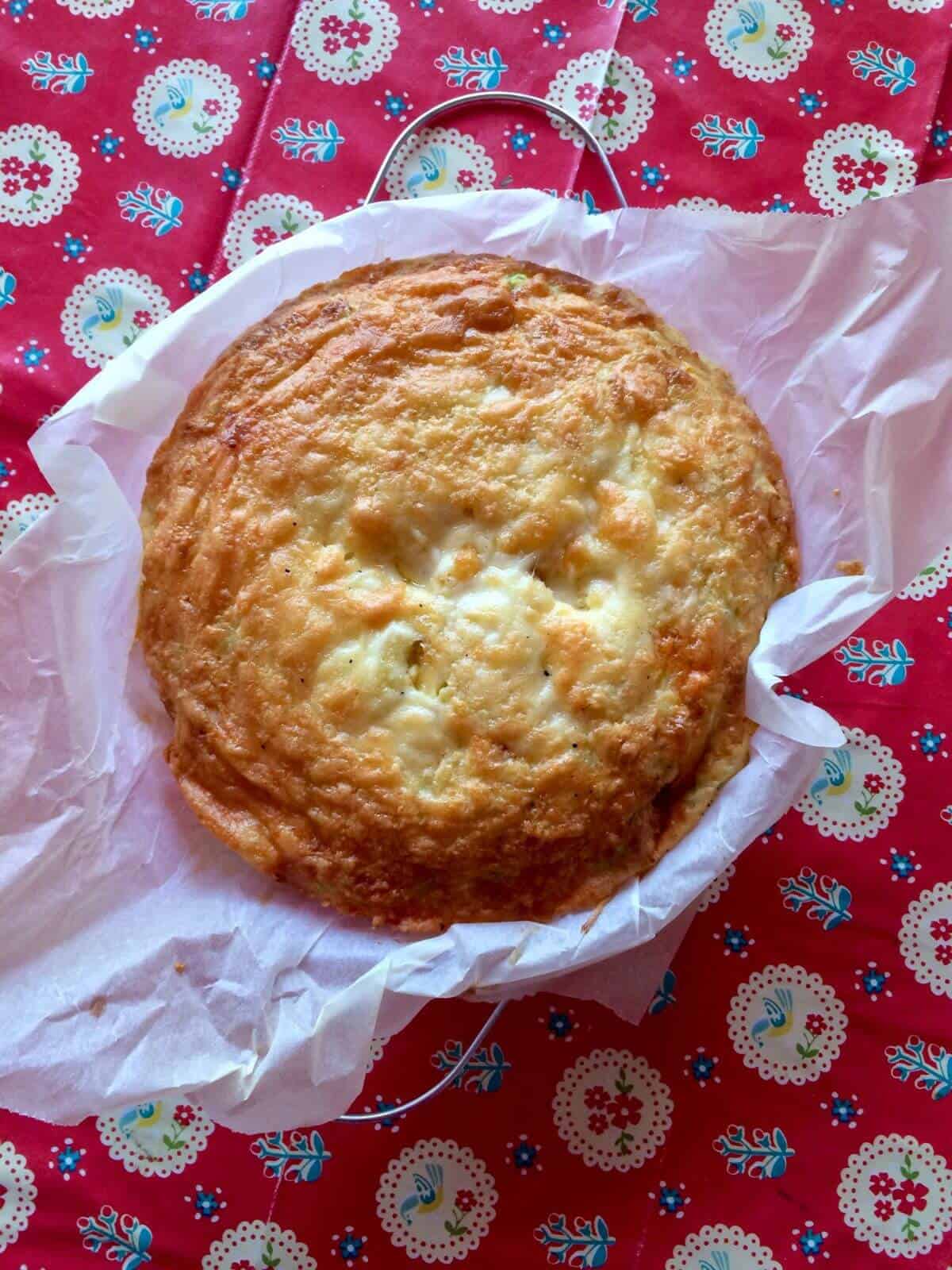 Photo from above of the cheesy chorizo crustless quiche surrounded by scrunched greaseproof paper on a bright red tablecloth with a folk pattern