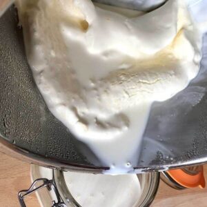 Homemade Clotted Cream being drained into a glass kilner jar after chilling