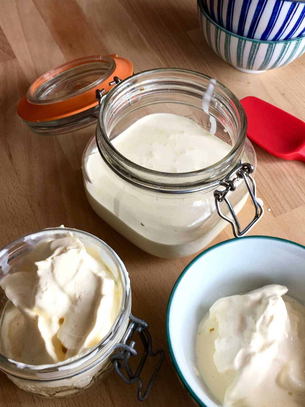 Photo from above of the clotted cream in a glass clip jar ready to store as well as in a bowl then he whey at the top of the photo in another glass clip jar, showing it makes tons