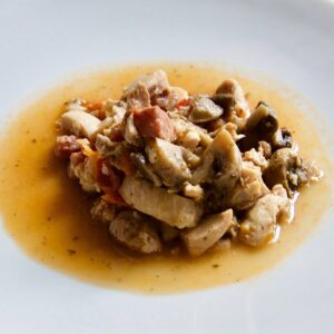 Pressure cooked Chicken and Serrano Ham surrounded by its juices on a white plate