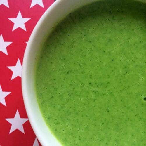 Watercress Soup seen from above in a white bowl against a red background with white stars