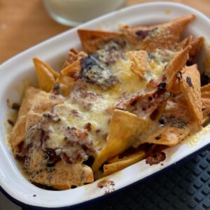 A white rectangular enamel dish full of cheesy loaded nachos