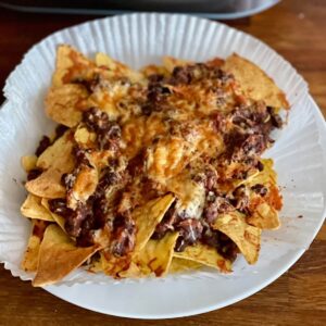 The air fried Ninja Speedi Nachos served on a white plate with the air fryer liner still underneath
