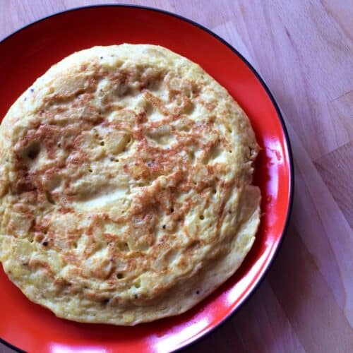 The tortilla de patatas (Spanish Potato Omelette) seen from above served on a round orange plate