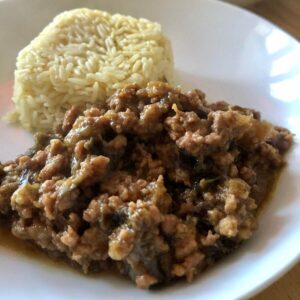 The pressure cooked Pork and Aubergine served on a white plate with a portion of rice shaped as a square