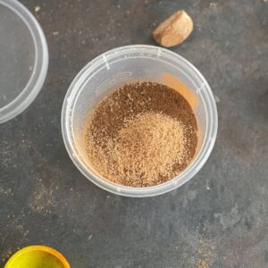 Photo of a little plastic pot containing the different spices that make the Baharat Spice Mix, ready to use