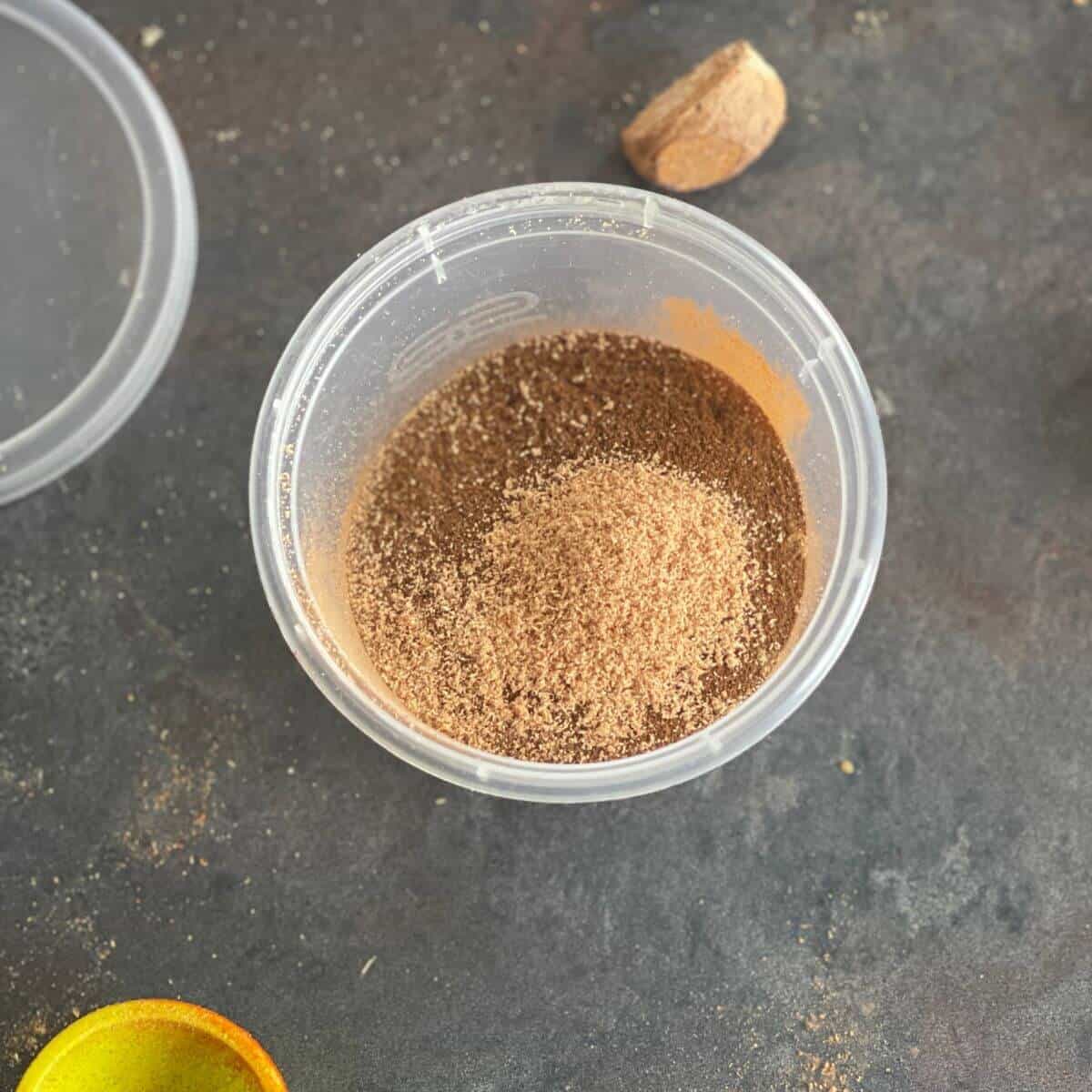Photo of a little plastic pot containing the different spices that make the Baharat Spice Mix, ready to use