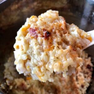 A large spoonful of pressure cooked Gammon rice with a delicious cheesy top being lifted away from the rest of the pot of rice