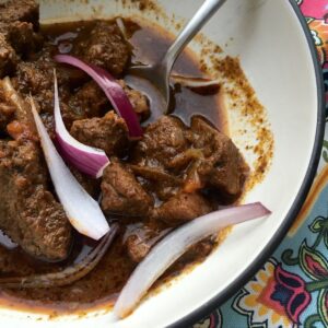 The Beef with Mexican Spices served with a few thin wedges of red onion in a beige bowl with dark rim against a colourful background