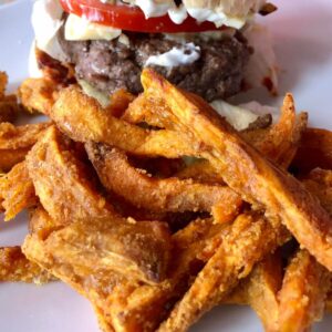Sweet Potato Fries air fried in the Instant Pot Duo Crisp and served on a white plate with a burger in the background