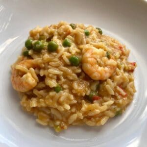 The Instant Pot Prawn, Trout and Pea Risotto with the rice, peas and a couple of king prawns ready to eat served on a shiny white plate