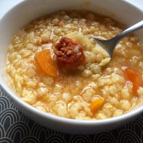 Pasta soup served in a white bowl, the star pasta and the chorizo make it very tempting and there carrot and chorizo stand out