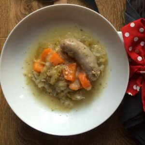 The sausage and apple casserole served on a white plate, should you need a good giggle it might be handy to know that the sausage looks rather phallic