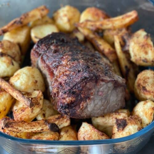 The large glass base of the Ninja Crispi with a roast beef joint surrounded by roast potatoes and parsnips