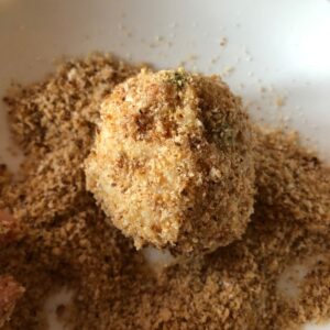 An arancini rice ball coated in and surrounded by breadcrumbs