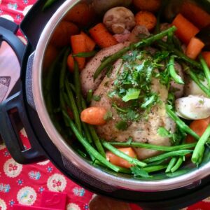 All the ingredients inside the Instant Pot ready to pressure cook, the chicken is in the middle and it's topped and surrounded by all the other ingredients