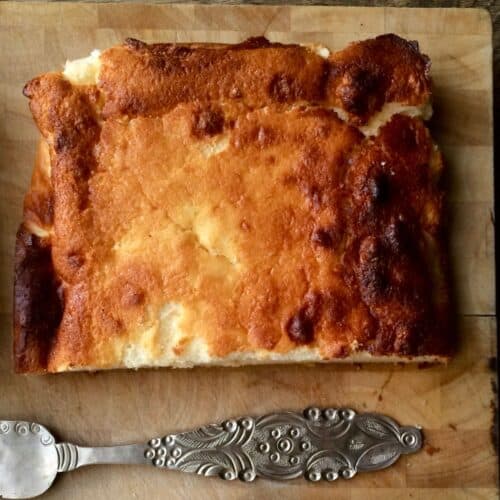 The Lemon Quark Cake from above with an ornate silver cake slice at the bottom of the photo