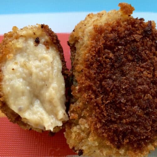 Two croquettes, one has been halved to reveal the creamy, thick béchamel inside